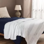 Покрывало и плед на кровати в комнате с теплым освещением